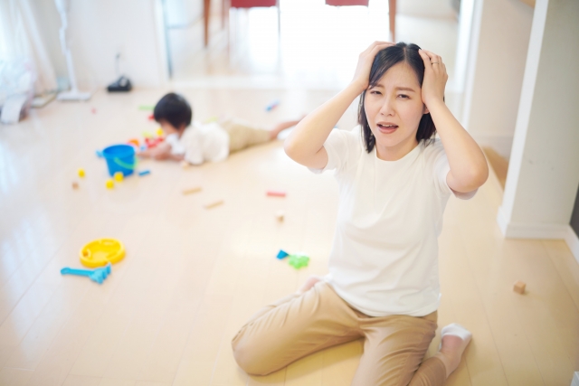 散らかった部屋で頭を抱える母親