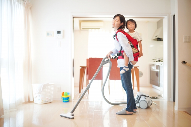 子どもをおんぶしながら掃除をする母親